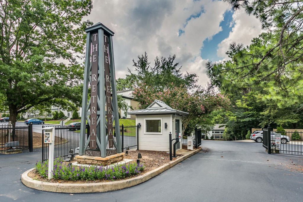 the entrance to a park with a monument and a small building