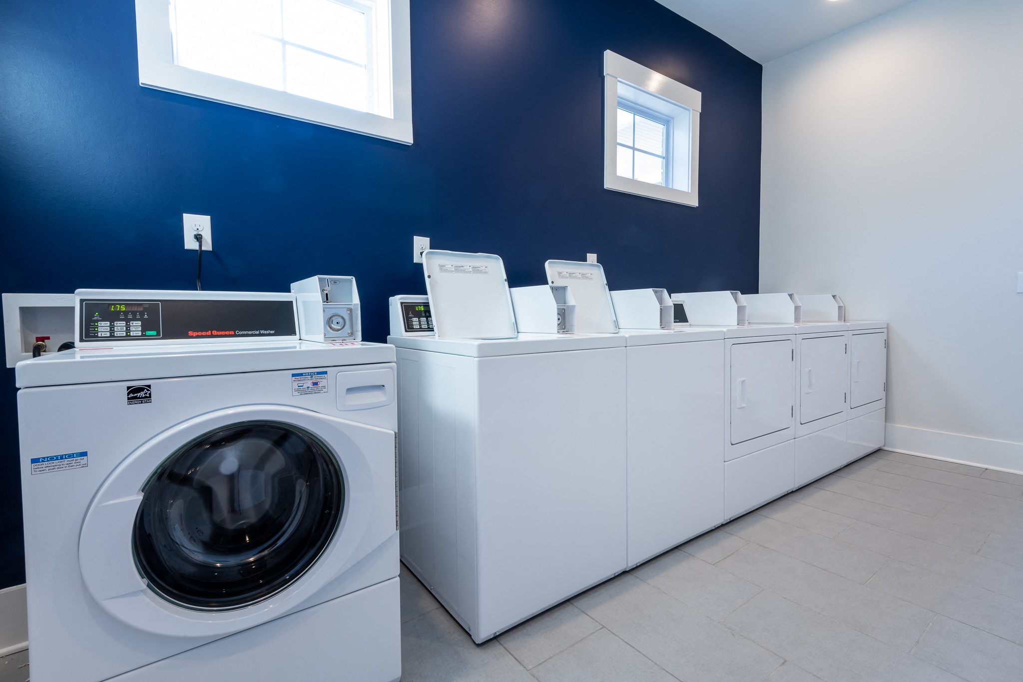 a laundry room with washers and dryers and a row of washing machines