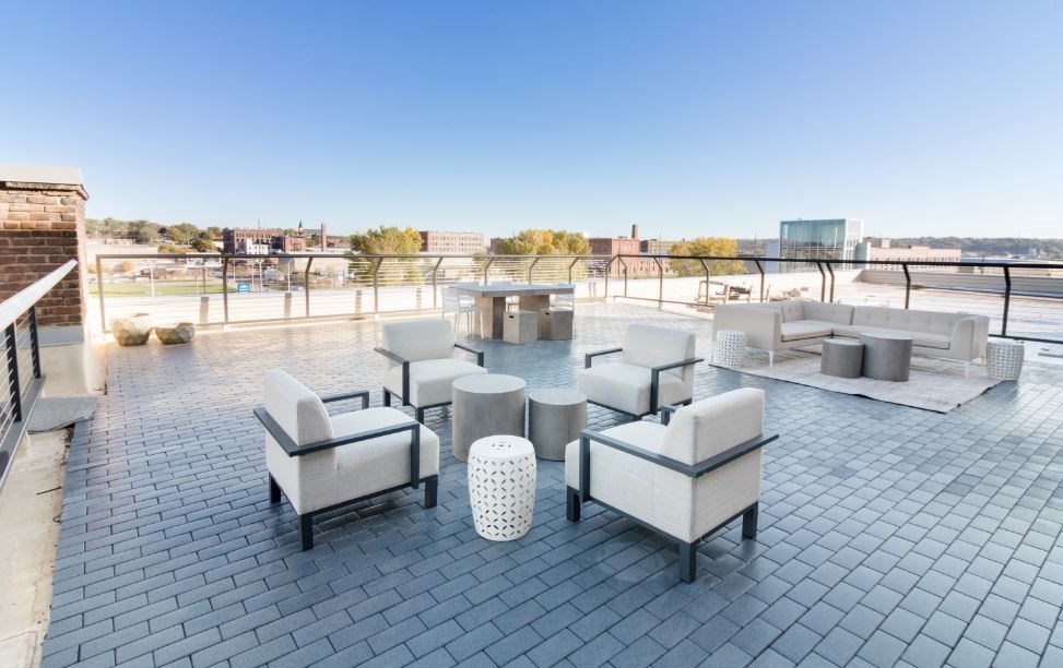 a rooftop patio with couches and chairs and a fire pit