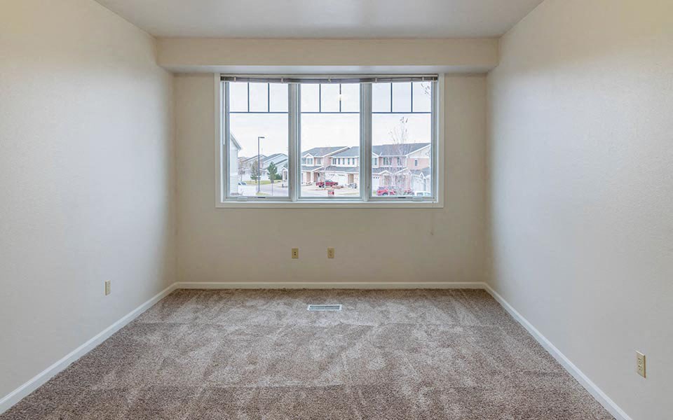 an empty room with a large window and carpet