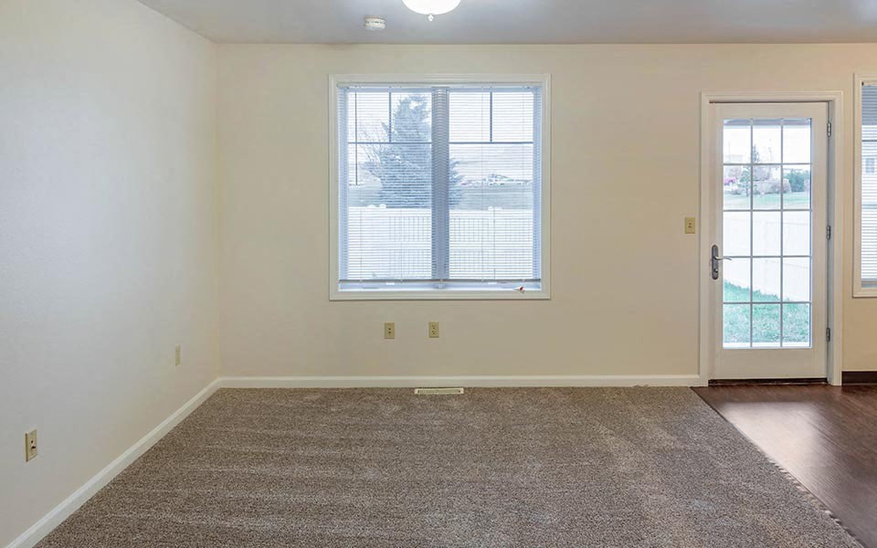 an empty living room with a window and a door