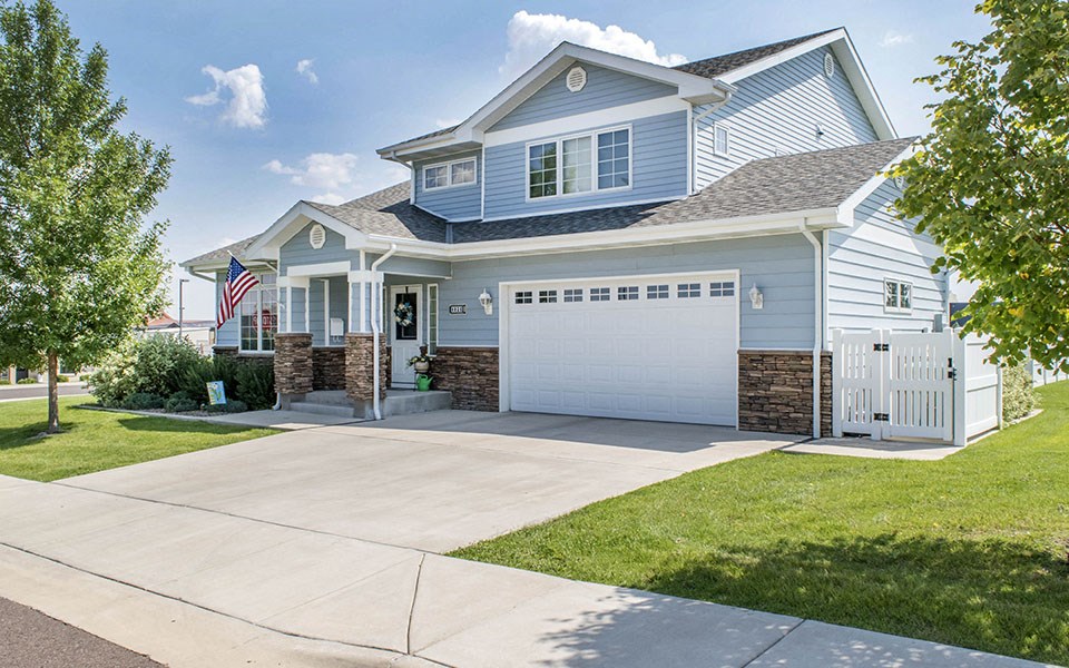 a blue house with a white garage door and a flag