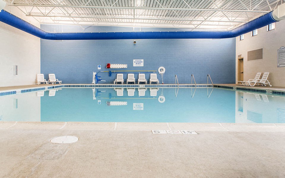 a swimming pool with chairs and a blue wall