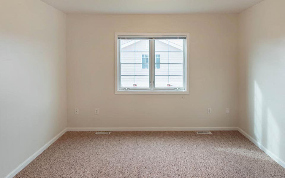 an empty room with a window and a carpet