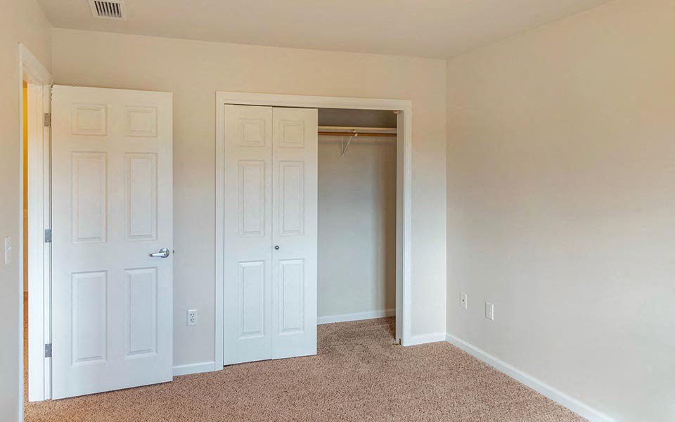 an empty room with white doors and a closet