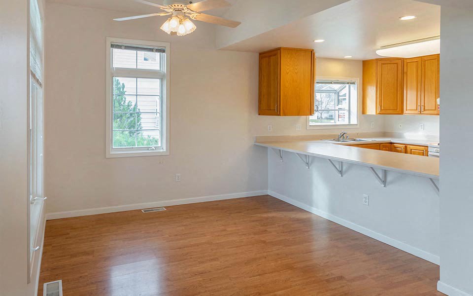 an empty living room and kitchen with a wood floor