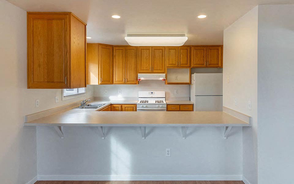 an empty kitchen with wooden cabinets and a counter top