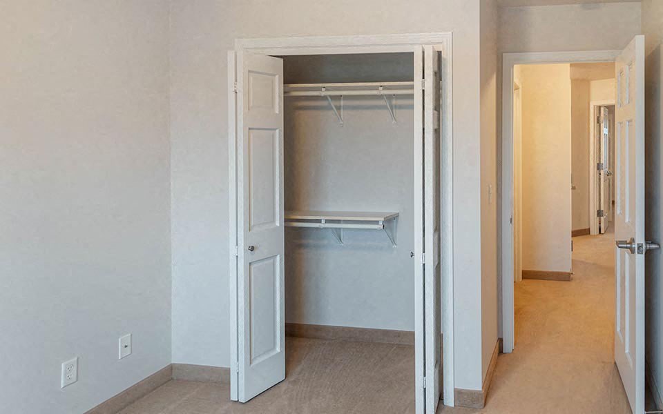 an empty closet in an empty room with doors open