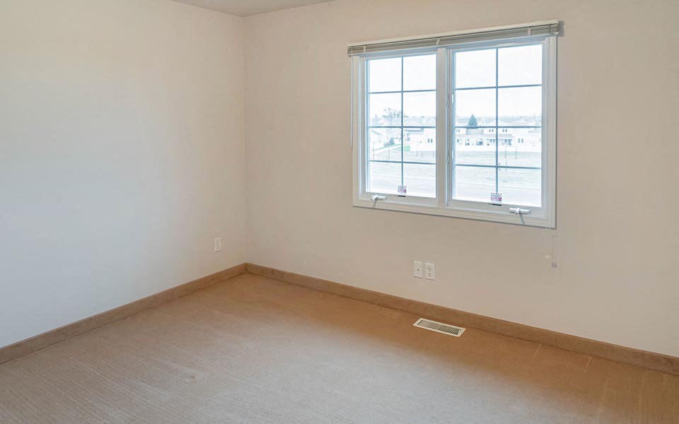 an empty room with a window and a wooden floor