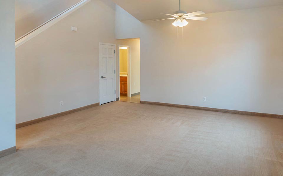 an empty living room with a ceiling fan