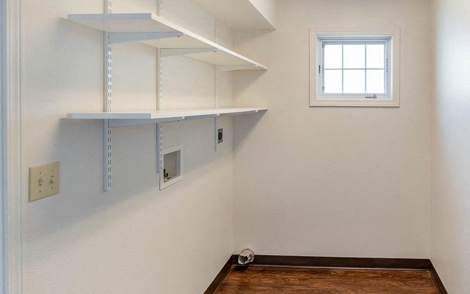 an empty room with a window and shelves on the wall