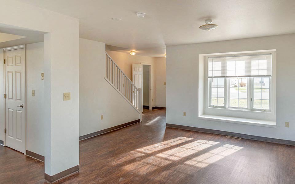 an empty living room with a large window and wood floors