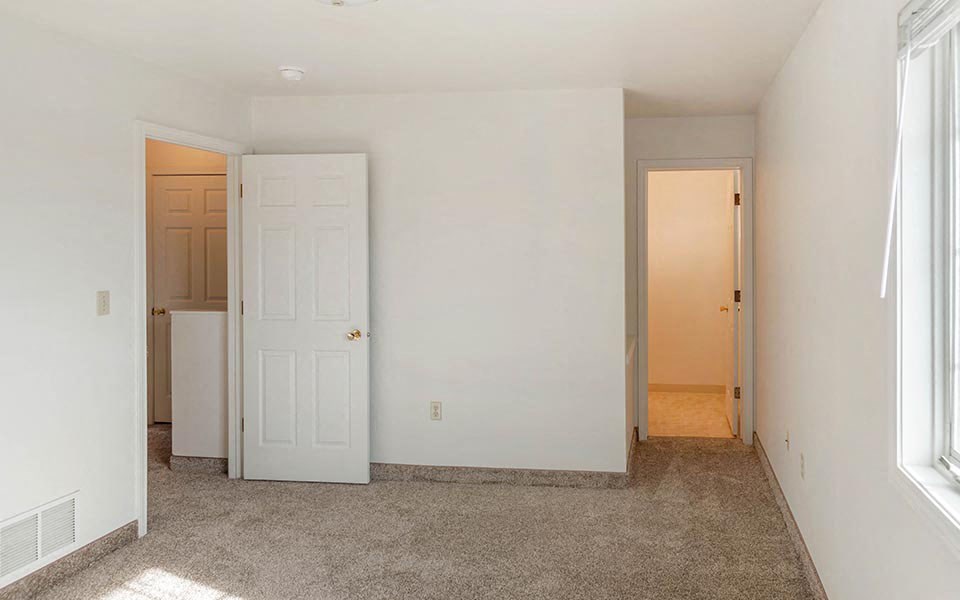 an empty room with a white door and a closet