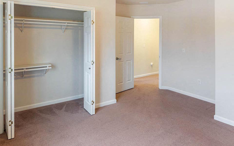 an empty bedroom with a closet and an open door