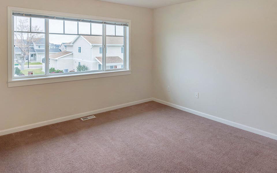 an empty room with a large window and a carpet