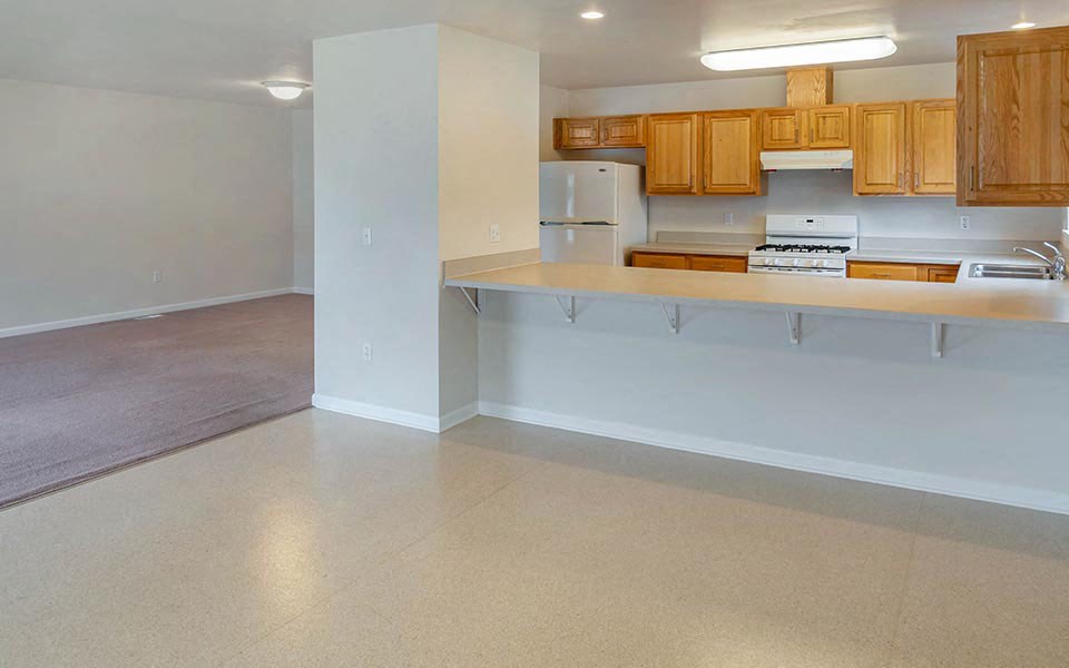 an empty kitchen and living room with wood cabinets