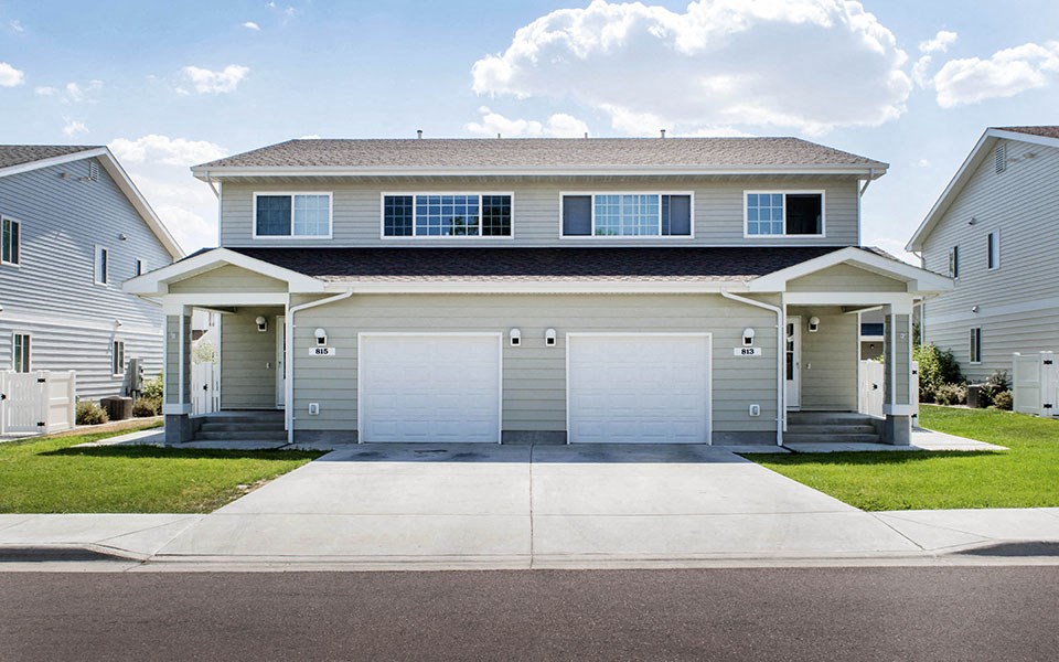 a white house with two garage doors on a driveway