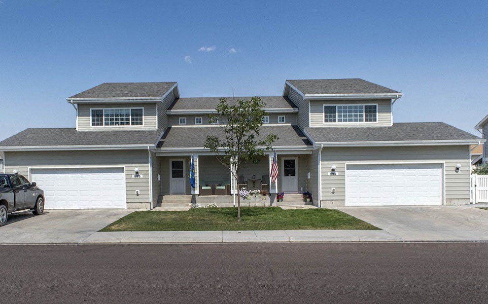 a house with white garage doors and a lawn