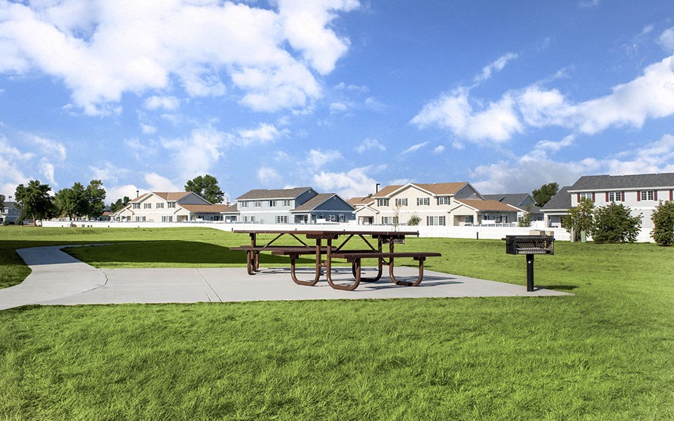 a picnic table in a park with houses in the background