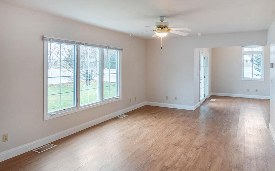 an empty living room with a ceiling fan and wood floors