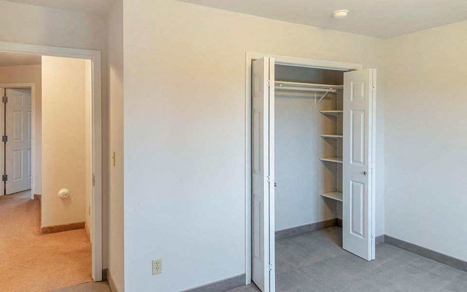 an empty bedroom with a closet and an open door