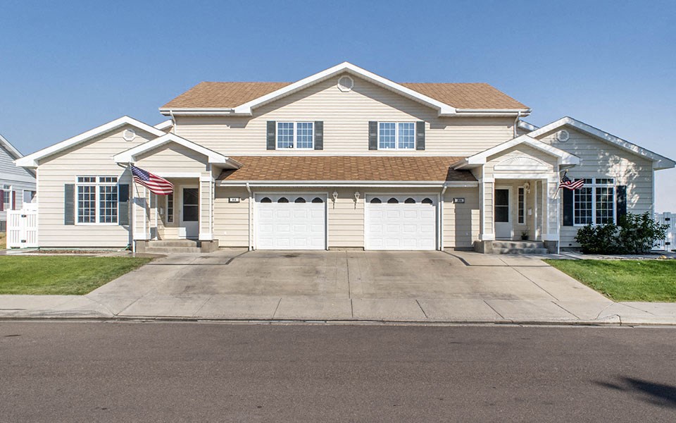 a white house with two garage doors and an flag
