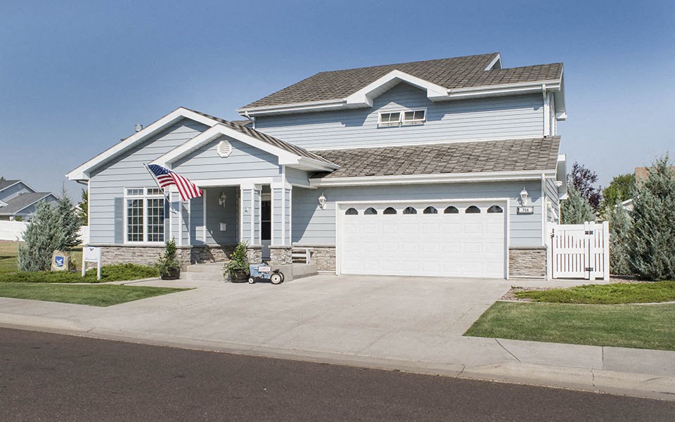 a blue house with an flag on the driveway