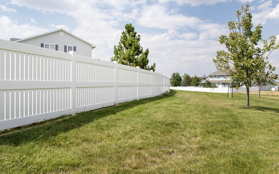 a white fence in a yard in front of a house