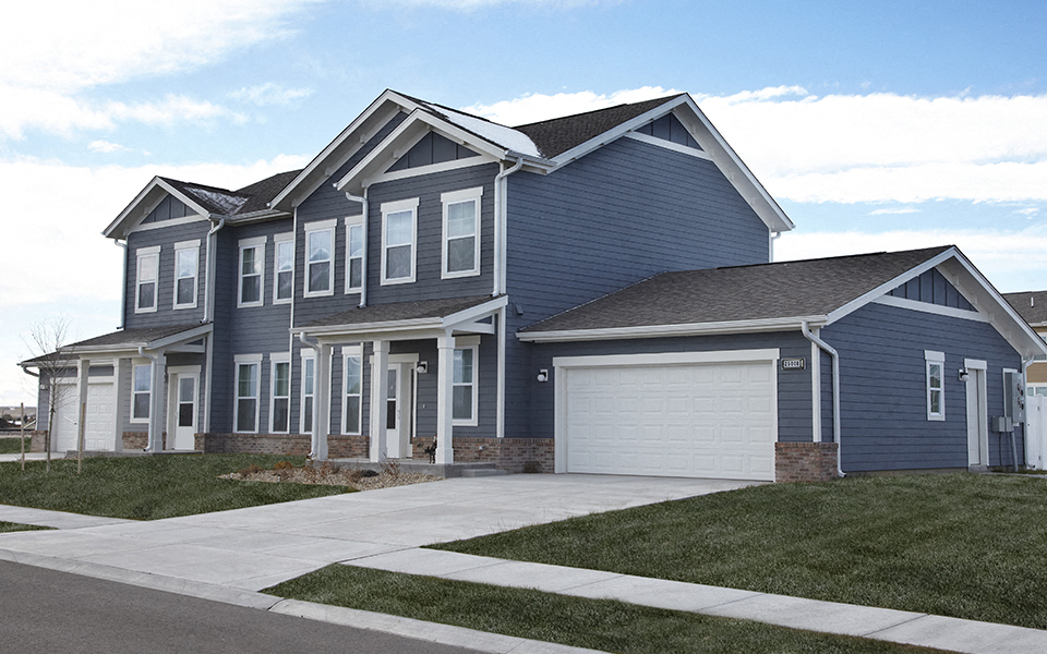 a blue house with a white garage door on a sidewalk
