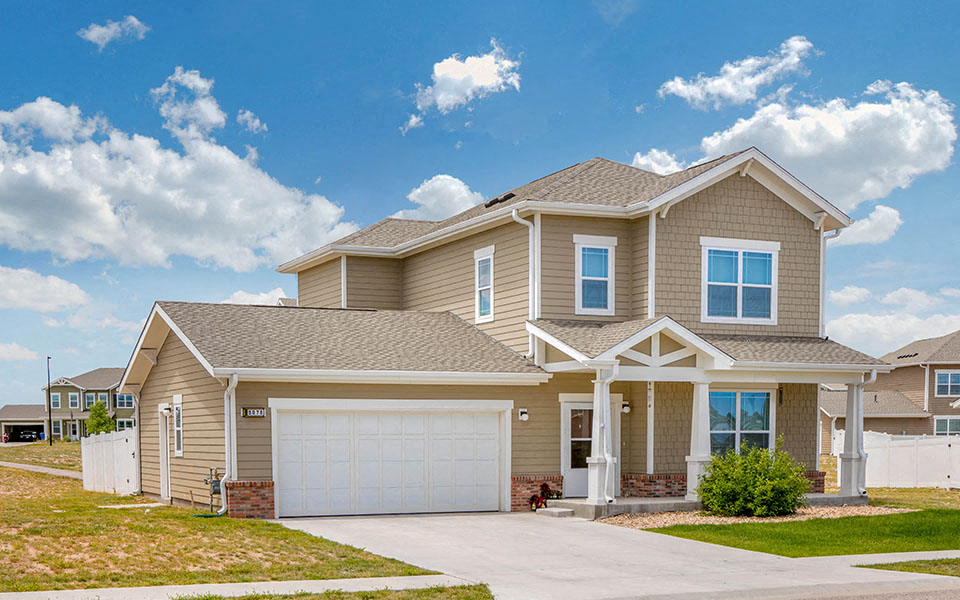 a tan house with a garage and a driveway