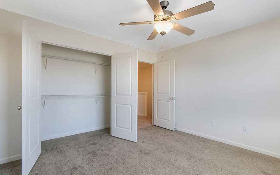 a bedroom with a closet and a ceiling fan