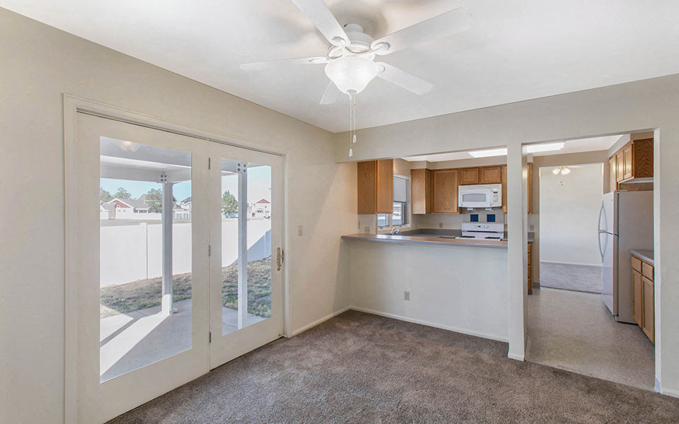 a living room with a kitchen and a ceiling fan