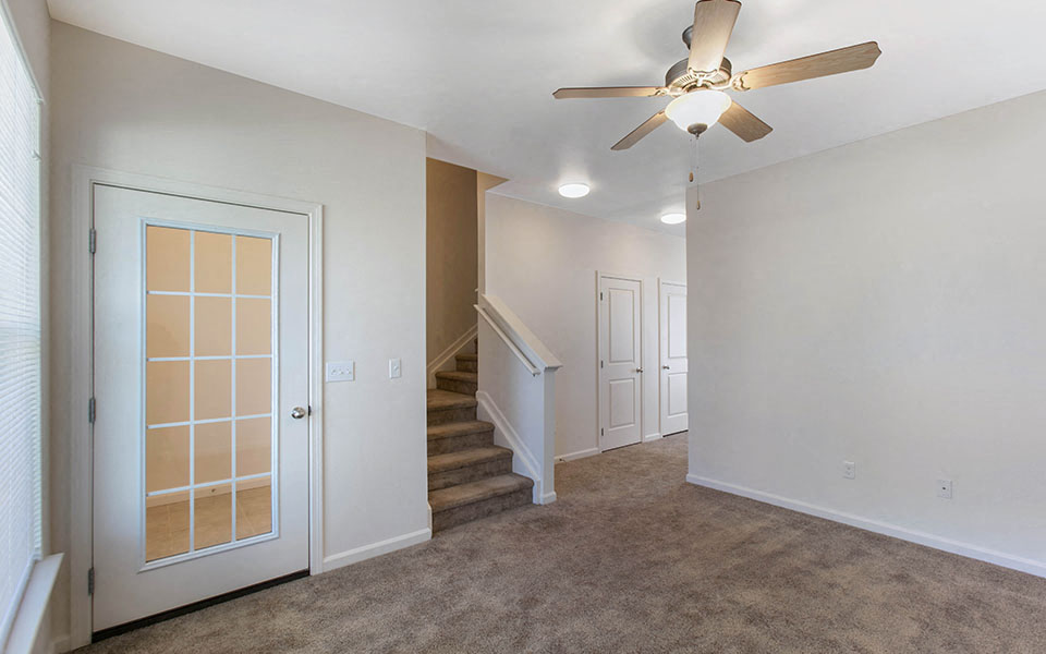 a living room with stairs and a ceiling fan