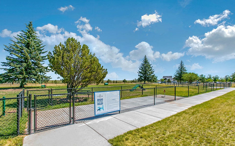 a park with a fence and a sign on a sidewalk