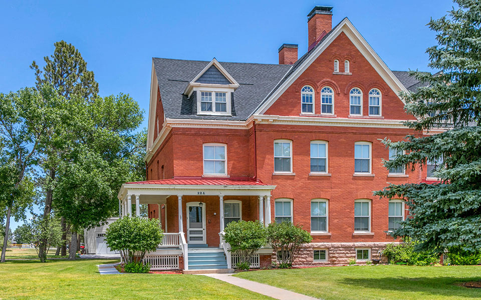 a red brick house with a porch and a green lawn