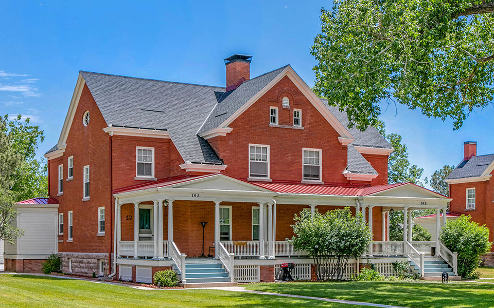 a red brick house with a porch and a tree