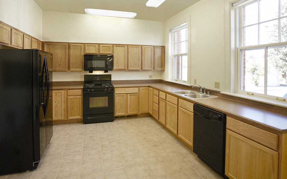 an empty kitchen with wooden cabinets and black appliances