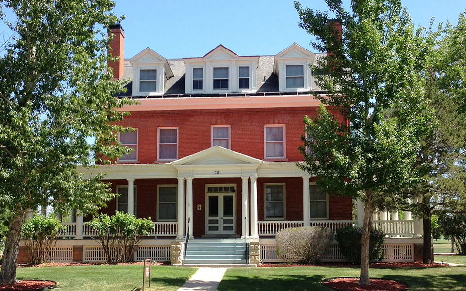 a red brick house with a white porch and trees