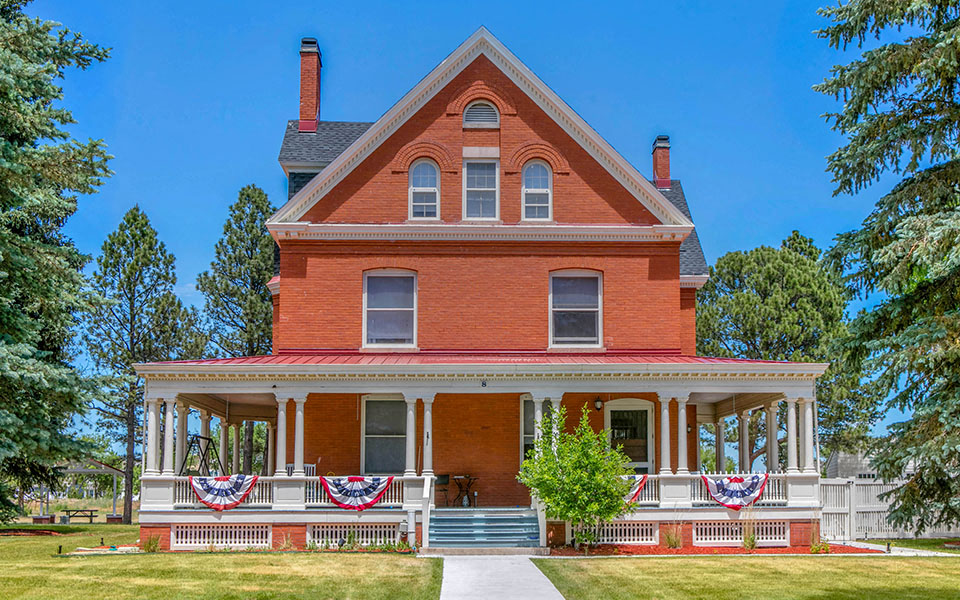 a red brick house with a porch with patriotic flags