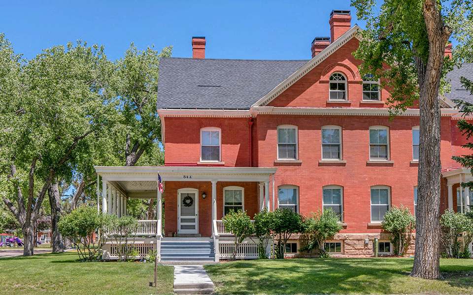 a red brick house with a porch and a tree