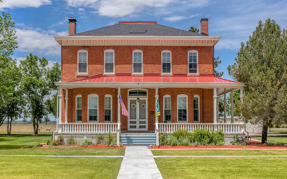 a large brick house with a red roof and a white sidewalk
