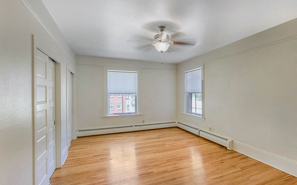 an empty living room with wood floors and a ceiling fan