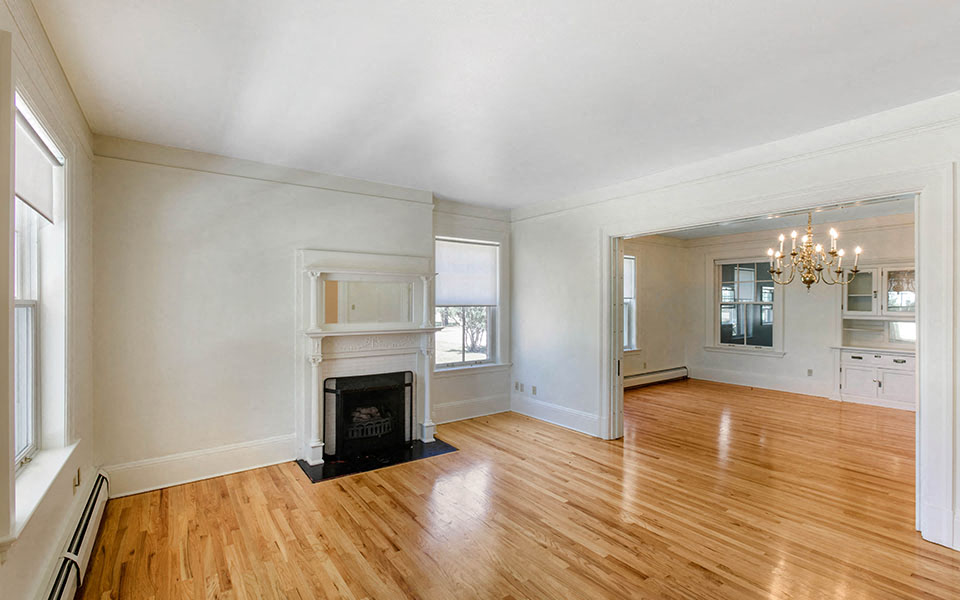 an empty living room with a fireplace and wooden floors