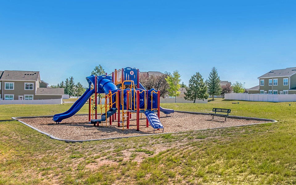 a playground with a blue playset in a park