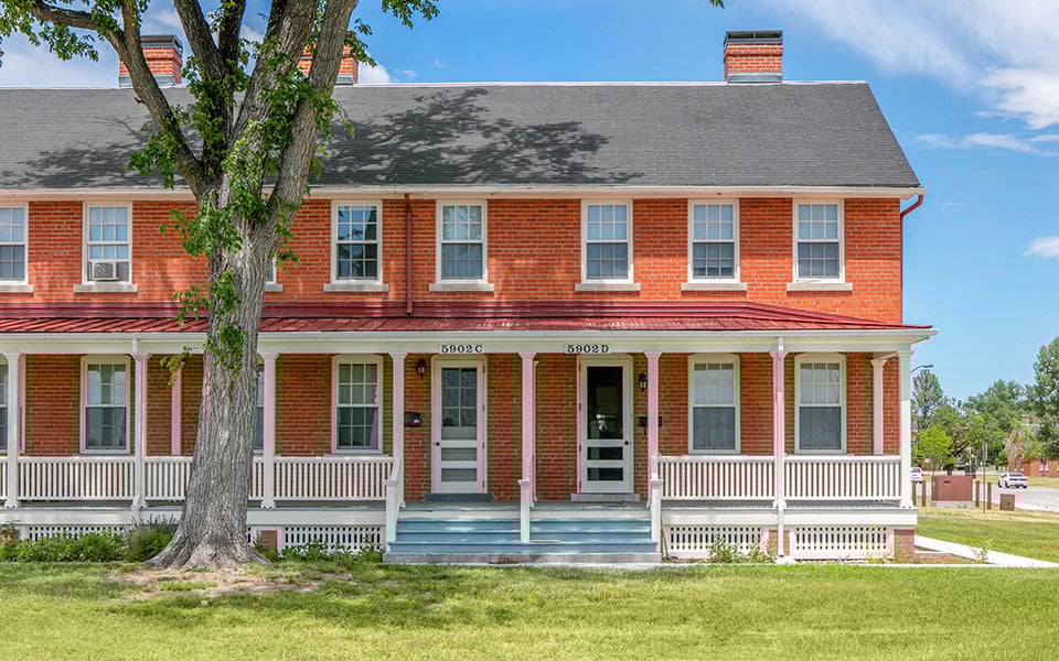 a red brick house with a tree in front of it