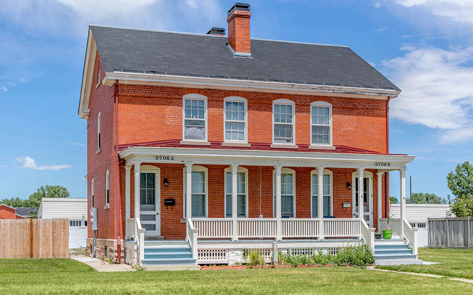 a red brick house with a porch and a black roof