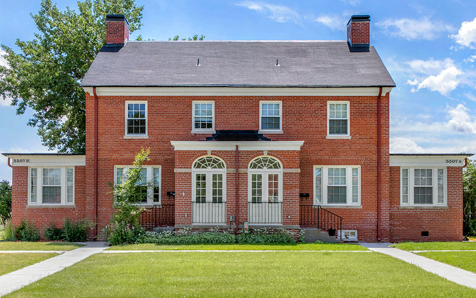 the front of a red brick house with a green lawn