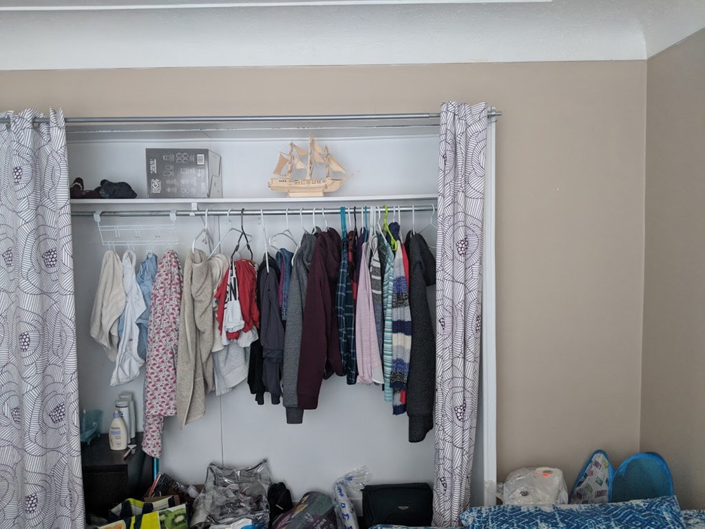 a closet filled with clothes and a rack of clothes hanging in it