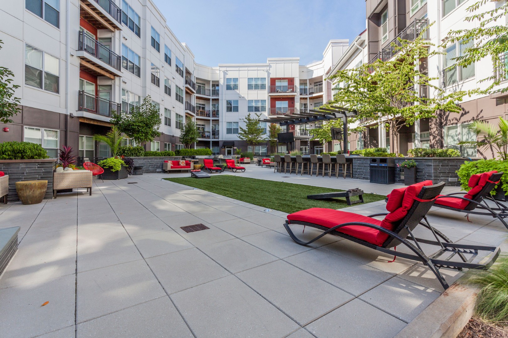 A patio with red chairs and a white building in the background.