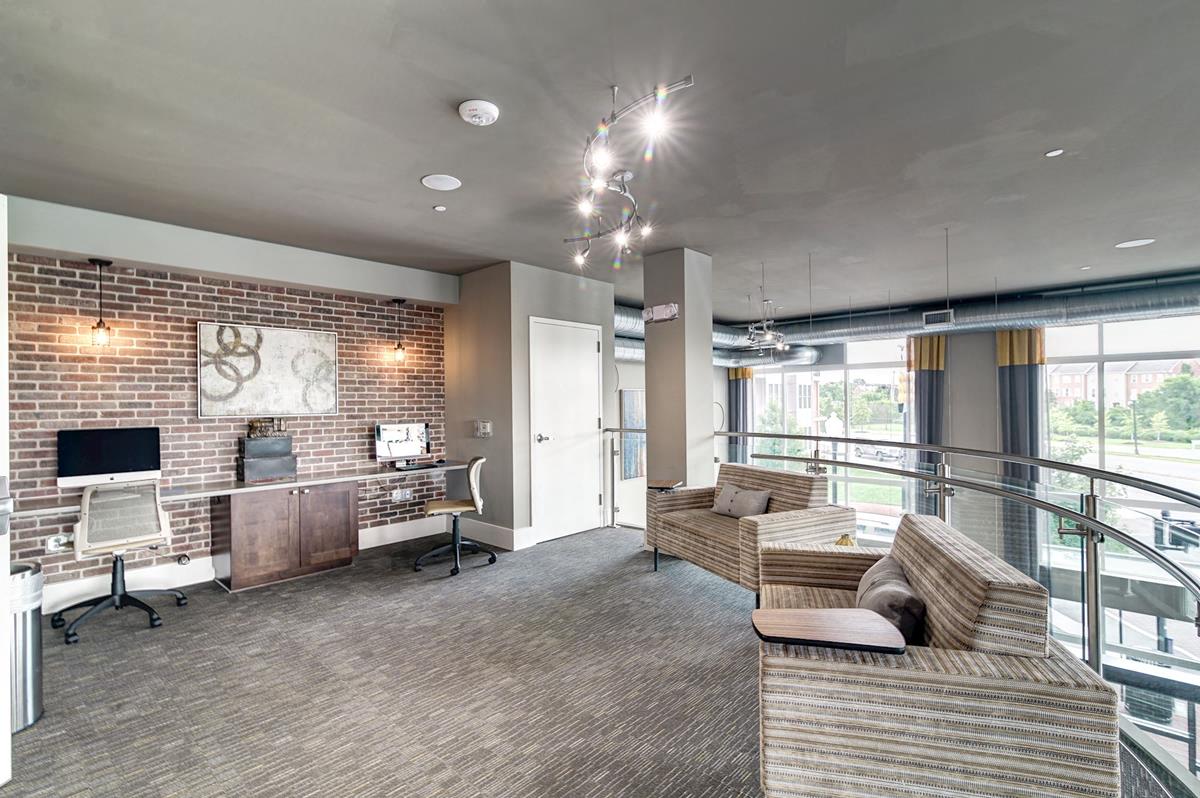 a living room with couches and a desk and a brick wall